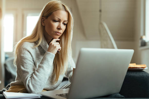 istock Pensive woman reading an e-mail while working on laptop at home. 1214712523