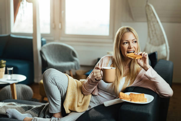 istock Young woman eating waffles and drinking coffee while relaxing at home. 1214712559