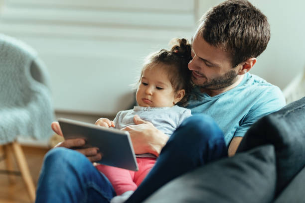 istock Young father with small daughter watching something on digital tablet at home. 1214713060