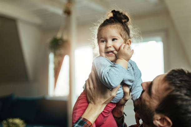 istock Cute small girl having fun with her father at home. 1214713066