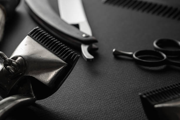 istock On a black surface are old barber tools. Two vintage manual hair clipper, razor, comb, shaving brush, hairdressing scissors. black monochrome. horizontal 1214716451