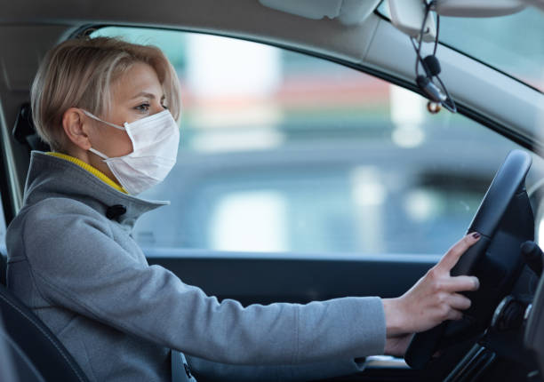 istock Woman wearing a face mask while driving a car 1214716452
