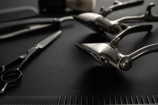 istock On a black surface are old barber tools. Two vintage manual hair clipper, comb, razor, shaving brush, hairdressing scissors. black monochrome. horizontal 1214717610