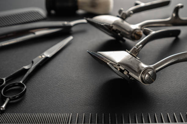 istock On a black surface are old barber tools. two vintage manual hair clipper, comb, razor, shaving brush, hairdressing scissors. black monochrome. 1214717637