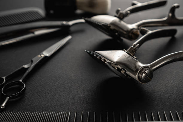 istock On a black surface are old barber tools. two vintage manual hair clipper, comb, razor, shaving brush, hairdressing scissors. black monochrome. 1214717663