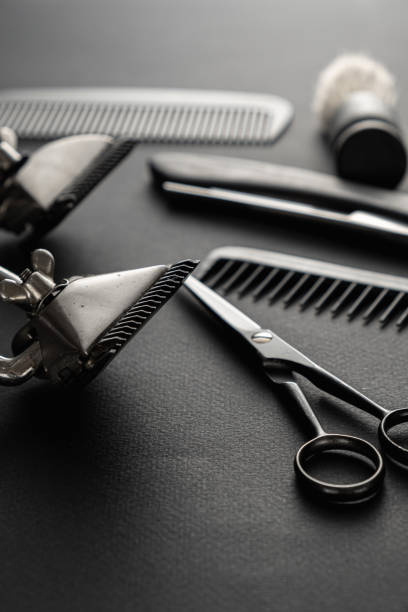 istock On a black surface are old barber tools. two vintage manual hair clipper, comb, razor, shaving brush, hairdressing scissors. black monochrome. vertical 1214717840