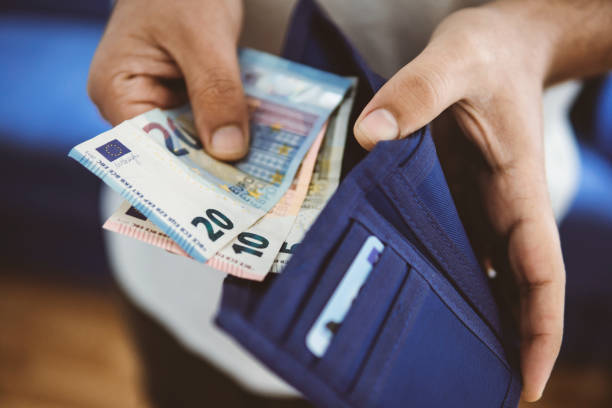 onherkenbare jonge man neemt geld uit zijn portemonnee - euro stockfoto's en -beelden