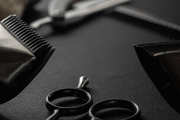 istock On a black surface are old barber tools. Two vintage manual hair clipper, razor, comb, shaving brush, hairdressing scissors. black monochrome. horizontal 1214718410