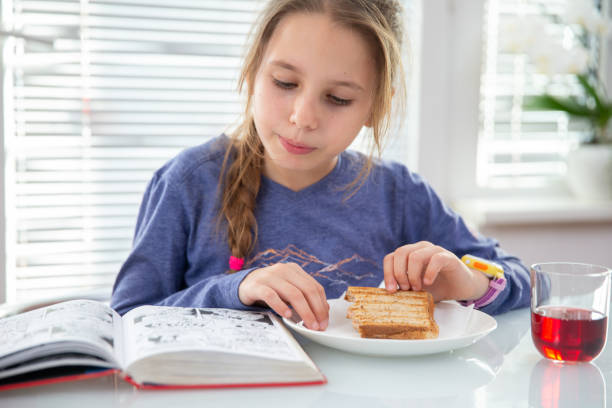 Little Girl Eating a Snack and Reading Comic Book Little Girl Eating a Snack and Reading Comic Book. reading comic book stock pictures, royalty-free photos & images
