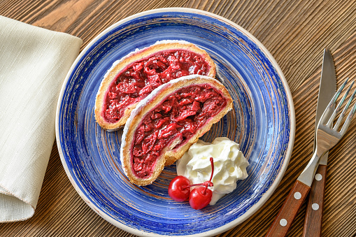 Slices of cherry strudel with whipped cream