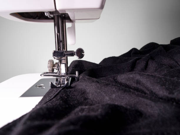 istock Sewing machine detail with a black fabric on a white wall background 1214723342