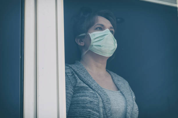 istock Woman wearing a protective face mask and looking out the window 1214723723
