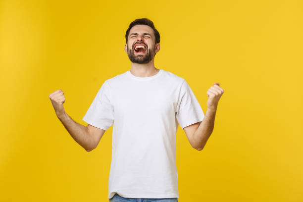 istock Happy young man with arms up isolated on a yellow background. 1214725439