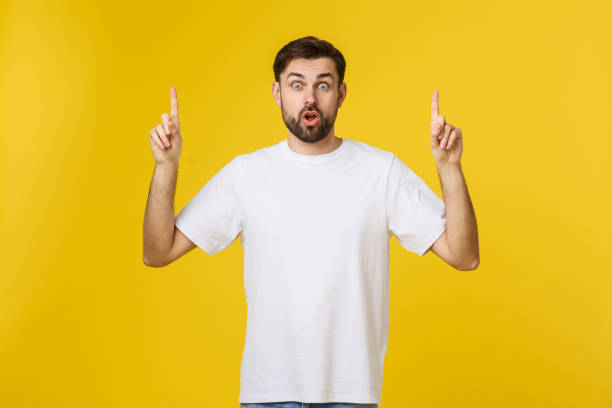 istock Young caucasian man pointing at something interesting on a yellow background 1214725469