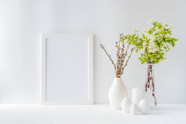 istock Home interior with easter decor. Mockup with a white frame and spring flowers in a vases on a light background 1214726926