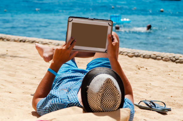 istock Young man freelancer relax doing his job on the beach using tablet computer 1214727903