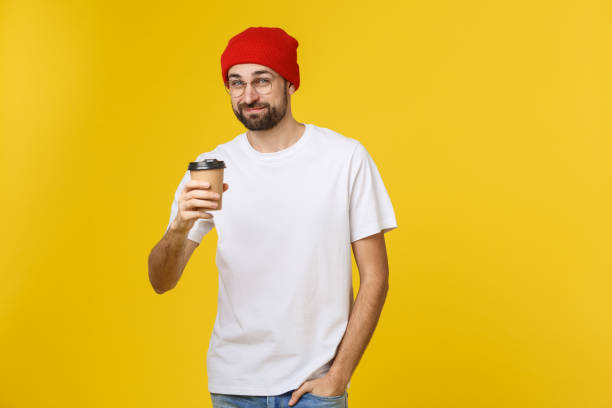 homme sur la couleur jaune vibrante isolée prenant un café dans la tasse de papier à emporter et souriant parce qu’il commencera bien la journée. - back against the wall photos et images de collection