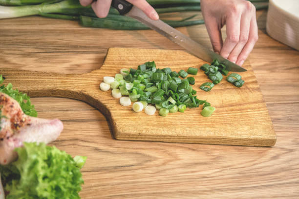 istock Female hand cutting green onions on board with knife 1214729761
