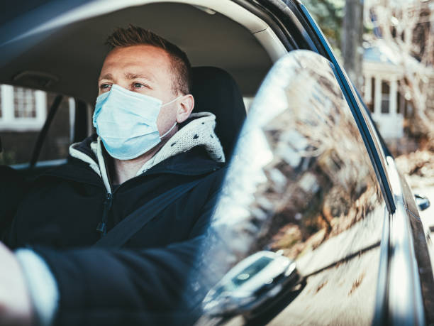 istock COVID-19, Young man wearing disposable face mask while driving 1214729999