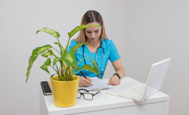 Confident nurse sitting in office. Confident young woman doctor. Intern nurse. Young pretty woman in white clothes with a stethoscope posing and smiling. Confident nurse sitting in office. Confident young woman doctor. Intern nurse. Young pretty woman in white clothes with a stethoscope posing and smiling. 9. Master’s Degree in Healthcare Administration stock pictures, royalty-free photos & images