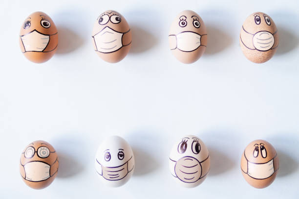 Diverse chicken eggs in with doodle faces wearing medical masks stock photo