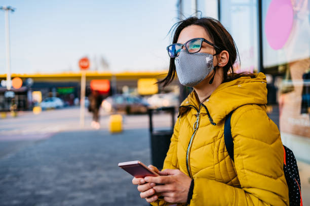 istock Woman in shopping mall with face mask using phone 1214731095