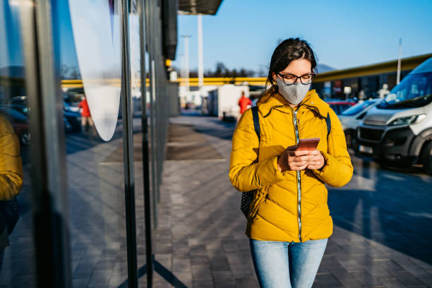 istock Woman in shopping mall with face mask using phone 1214731829