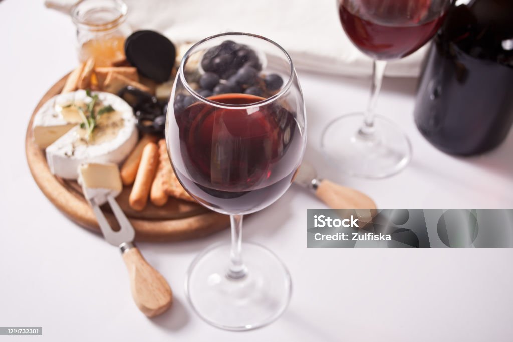赤ワイン2杯とプレート、チーズ、フルーツ、その他のスナックを合わせ、パーティーに - 赤ワインのロイヤリティフリーストックフォト