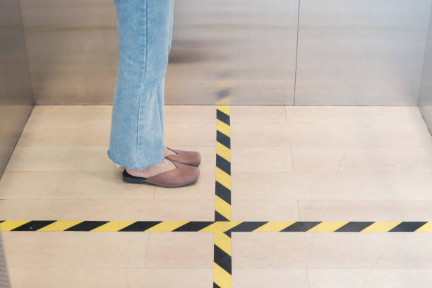 istock People stand on designated areas to ensure social distancing inside an elevator 1214734916