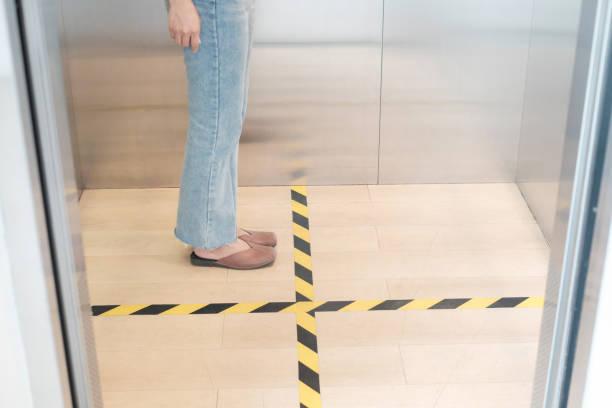 istock People stand on designated areas to ensure social distancing inside an elevator 1214734985