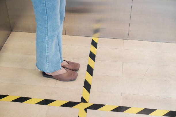 istock People stand on designated areas to ensure social distancing inside an elevator 1214735008