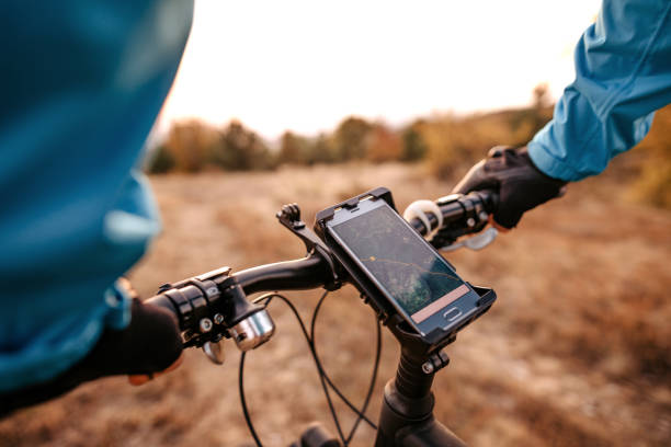 Mid adult man using navigational system while riding bicycle Biker in blue jacket sitting on bike while using navigational system extreme sports technology stock pictures, royalty-free photos & images