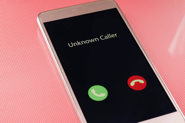 Unknown caller. White smartphone with incoming call from an unknown number on a red background. Incognito or anonymous stock photo
