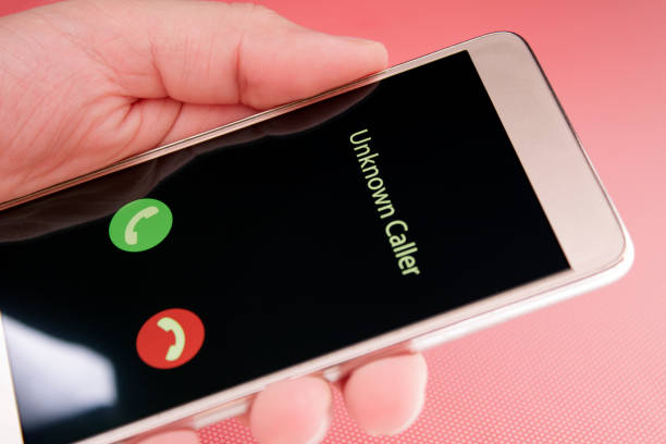 Unknown caller. A man holds a phone in his hand and thinks to end the call. Incoming from an unknown number at night. Incognito or anonymous stock photo