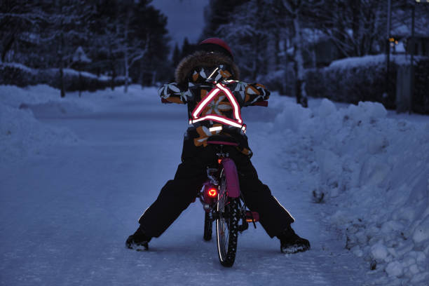 冬の夜に自転車に乗った女の子。照明は、衣類の反射器や自転車の車輪から反射されます。暗い時��間の安全なサイクリング。 - road reflector ストックフォトと画像