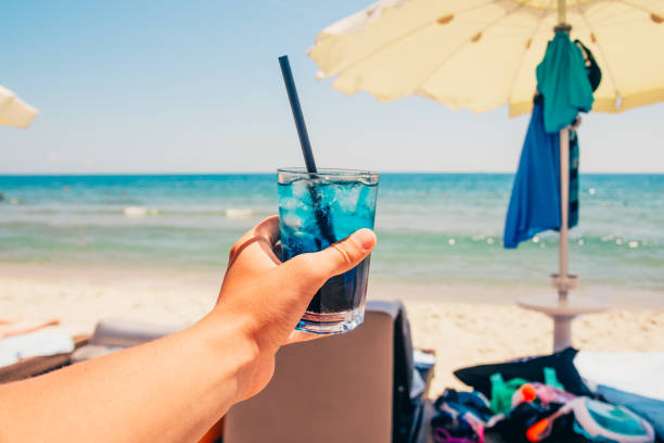 blue refreshing cocktail at the beach in hand