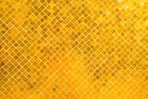 Wall surface with many gold shiny mosaic squares. Can be used as metallic background