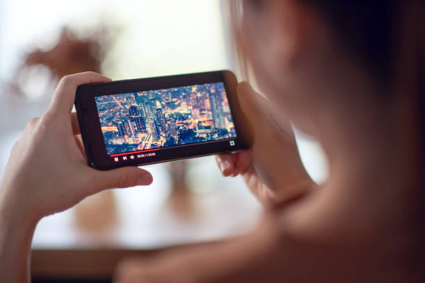 transmisión de películas en línea con smartphone. mujer viendo película en el teléfono móvil con servicio de reproductor de vídeo imaginario. - ipad women human hand digital tablet fotografías e imágenes de stock