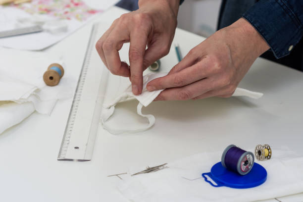 istock Seamstress is sewing a  face mask of white material 1214751729