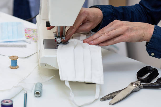 istock Seamstress is sewing a  face mask of white material 1214751750