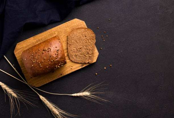 istock bread on a wooden board on a black background. copy space 1214752416