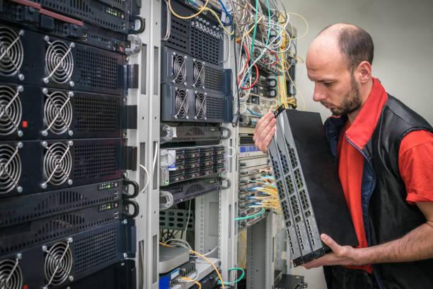 istock The installer works in a data center. Technology concept. A technician holds in his hands a lot of Internet network equipment. A man installs new switches in the server room. 1214753278