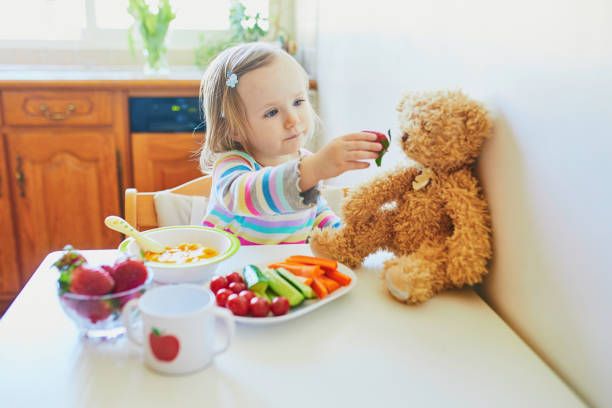 очаровательный малыш девушка ест свежие фрукты и овощи на обед - baby carrot snack healthy eating small стоковые фото и изображения