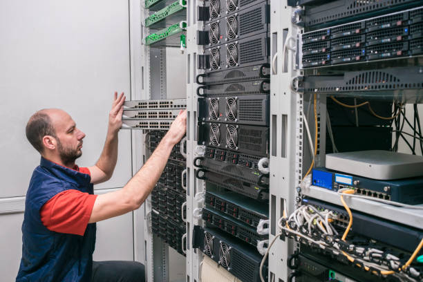 istock Technician was crouched down near computer racks. Engineer installs new switches in the server room. A man sets up server hardware in a modern data center. 1214753539