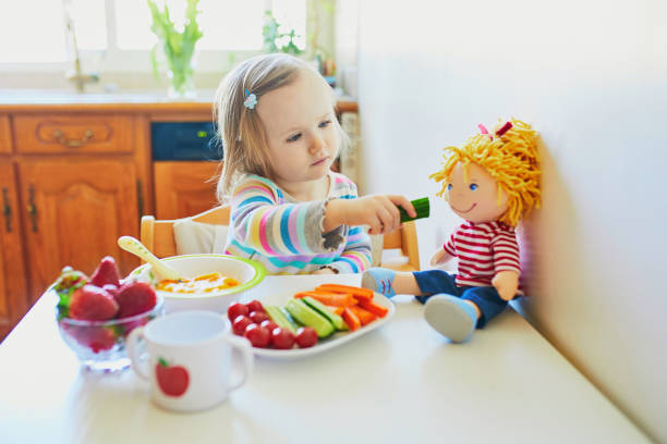 очаровательный малыш девушка ест свежие фрукты и овощи на обед - baby carrot snack healthy eating small стоковые фото и изображения