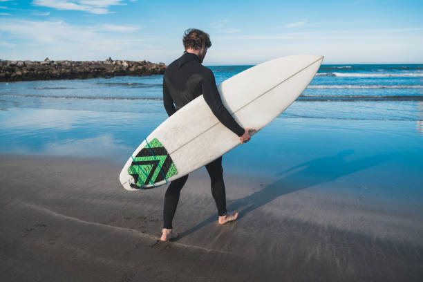 istock surfer entering into the water with his surfboard. 1214753601