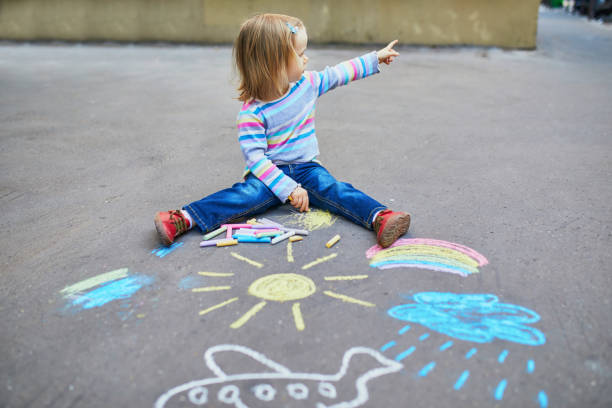 adorabile bambino ragazza disegno con gessi colorati su asfalto - little girls sidewalk child chalk foto e immagini stock