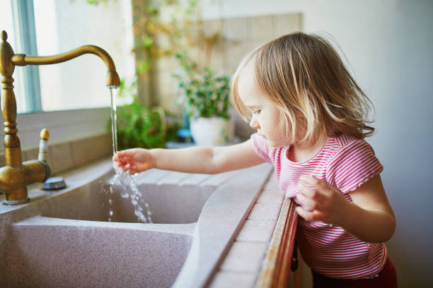 istock toddler girl washing her hands under kitchen sink 1214753661