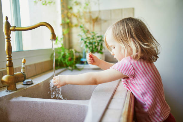 istock toddler girl washing her hands under kitchen sink 1214753700