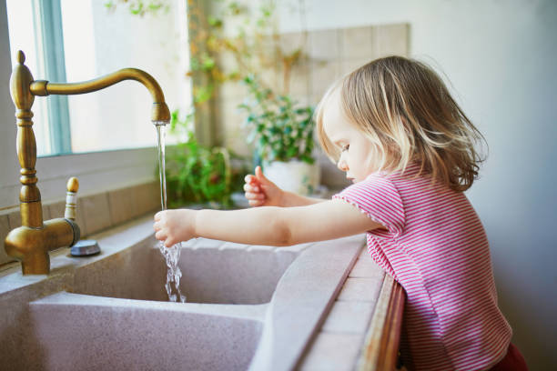 istock toddler girl washing her hands under kitchen sink 1214753715